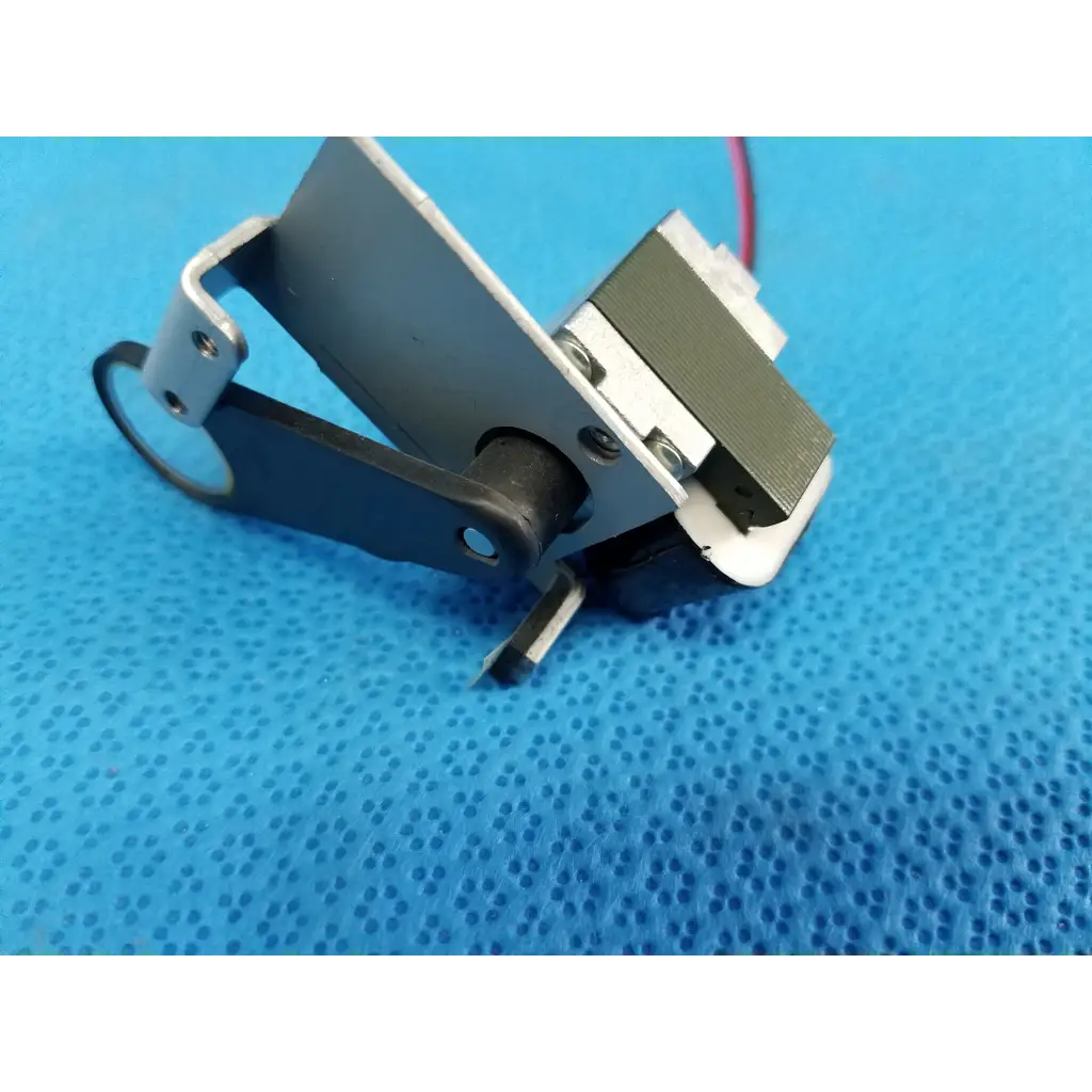 Black and silver rotary solenoid filter shutter with white plastic component and red wire for Topcon TRC-NW8 fundus camera