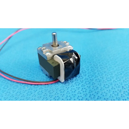 Black and silver stepper motor with metallic shaft and exposed wiring for internal Takano rotary solenoid used in fundus retinal camera