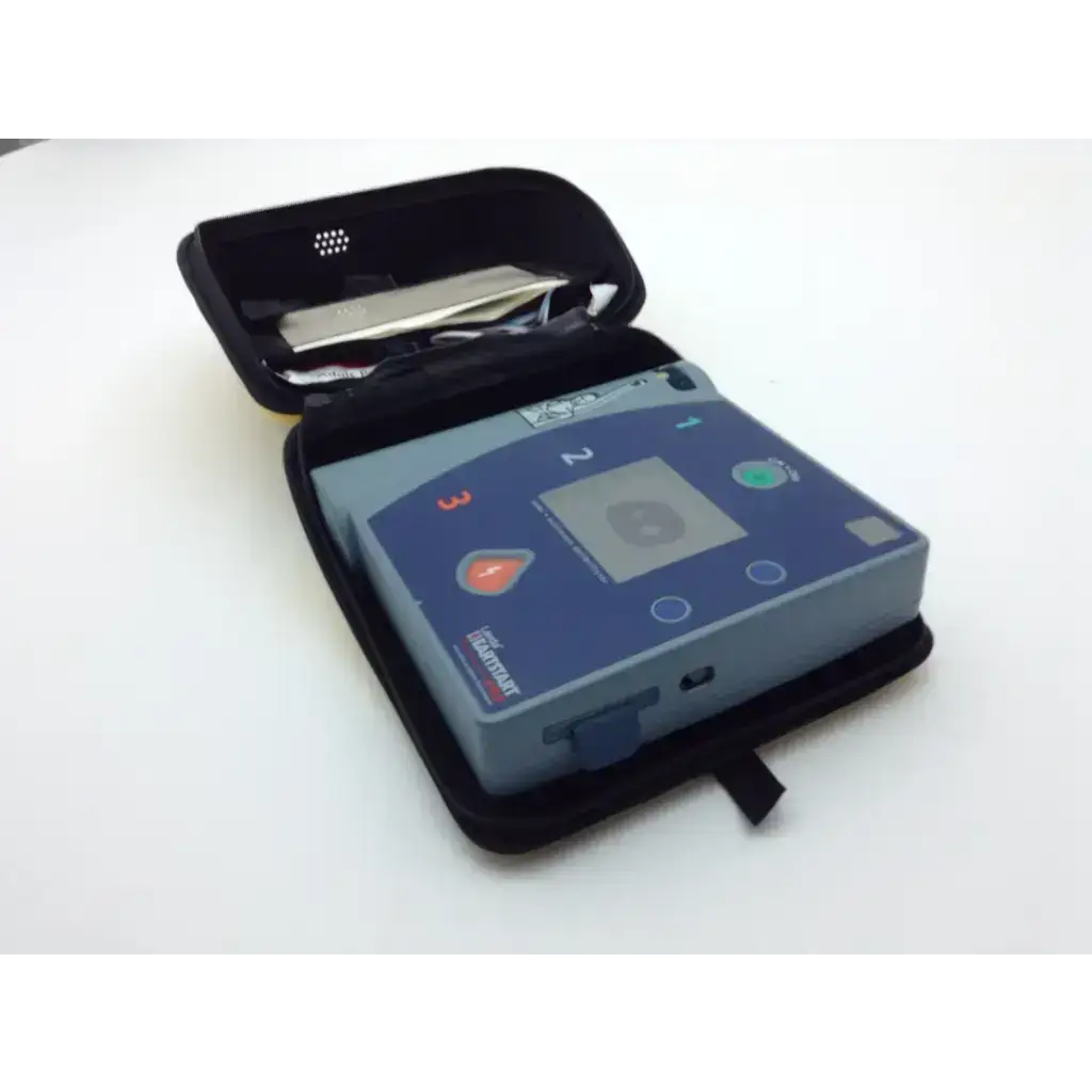 Blue and gray laerdal heartstart fr2 defibrillator device in black carrying case with pads battery and data card tray