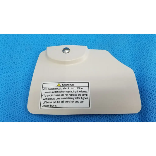 Off-white plastic lamp house cover panel with silver screw and caution label for Topcon TRC-NW8 retinal camera