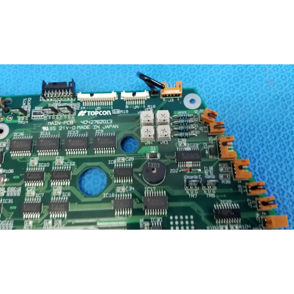 Green motherboard circuit board with black and orange connectors and silver capacitors for Topcon retinal camera