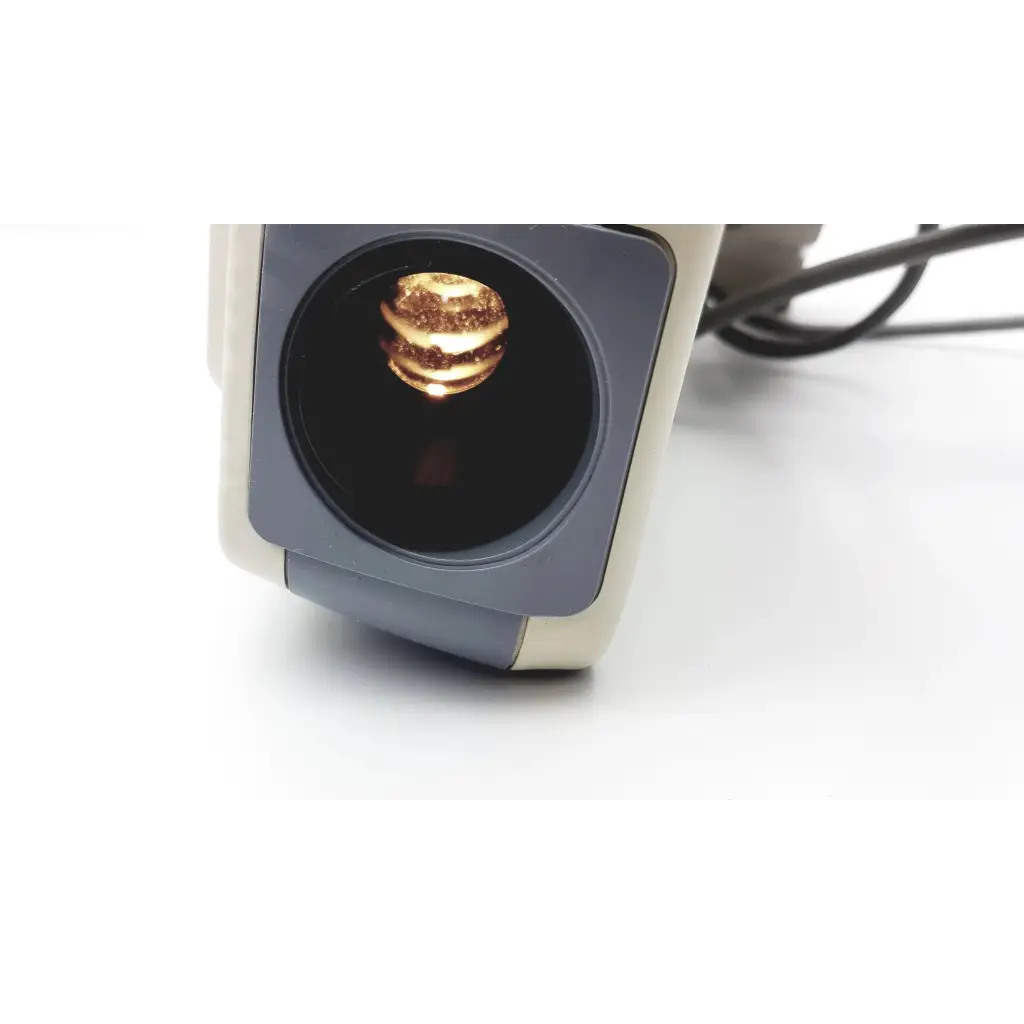 A golden layered burger-shaped object inside the circular aperture of the marco cp-690 auto chart projector scanner
