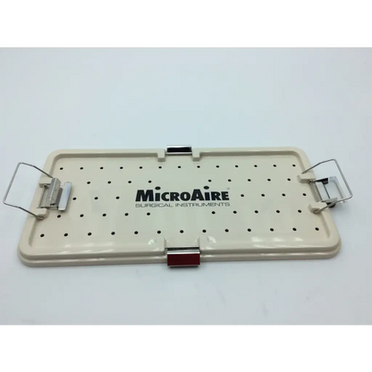 Cream-colored plastic surgical instrument tray with black perforated holes and metal clamps from micro aire surgical instruments