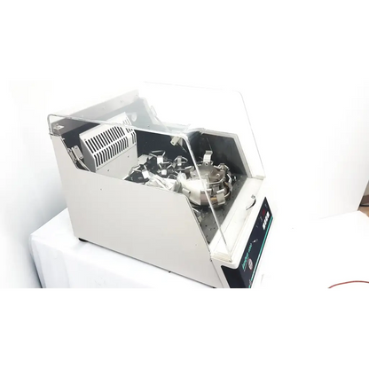 Silver-colored laboratory vortex mixer with transparent acrylic lid and black control panel in brunswick scientific innova incubator
