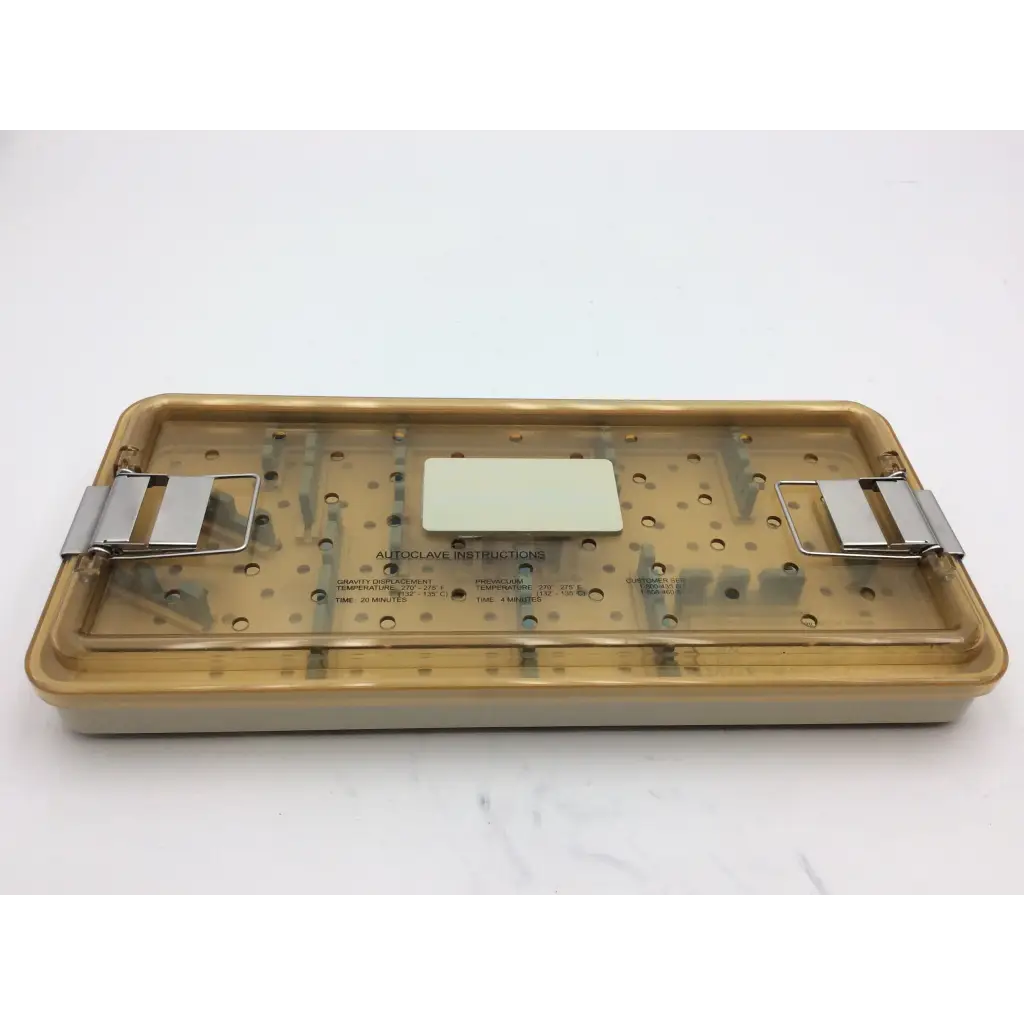 Beige plastic olympus autoclave instrument tray with metallic clamps and central label for sterilizing tools