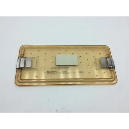 Translucent gold-colored plastic olympus autoclave instrument tray with metal clamps and white label for sterilization use