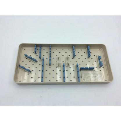 Beige plastic olympus autoclave instrument tray with blue and silver metal clamps arranged in a grid pattern