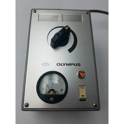Silver metallic Olympus Tokyo TF adjustable lamp power supply with black rotary dial, analog gauge, and red indicator light
