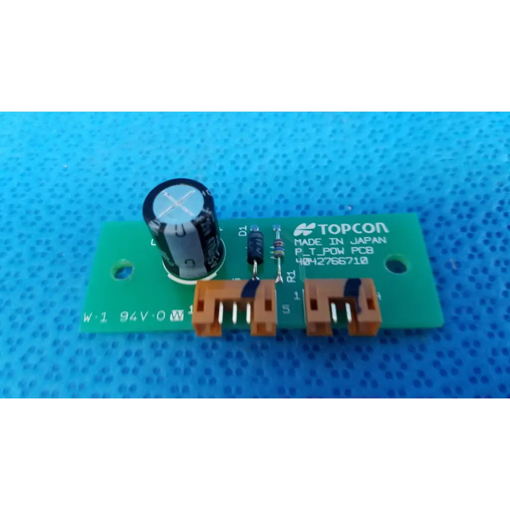 Green rectangular power circuit board with black capacitor and orange connectors labeled topcon p_t_pow pcb for retinal camera