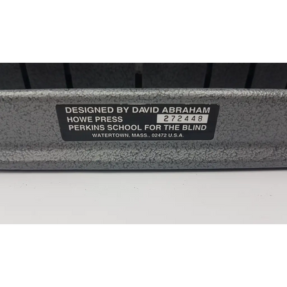 Gray textured metal back of perkins classic brailler with black label from blind howe press watertown massachusetts