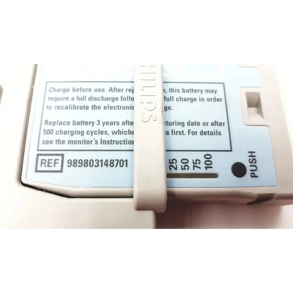 Beige philips intellivue m4607a mp2 battery module with white label showing charging instructions and push button