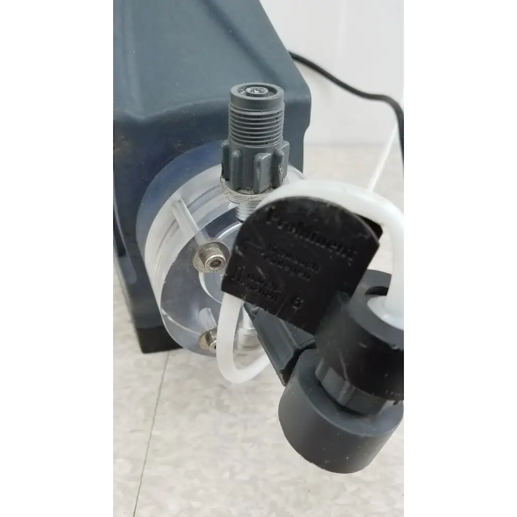 Black plastic ProMinent Gamma X GMXA 1009 diaphragm metering pump with transparent chamber and white tubing connected