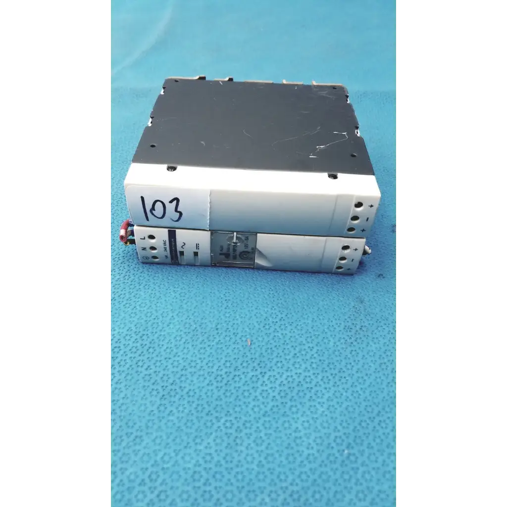 Stacked schneider electric abl7 rp1205 switch mode din rail power supplies with white and black casings and labeled terminals