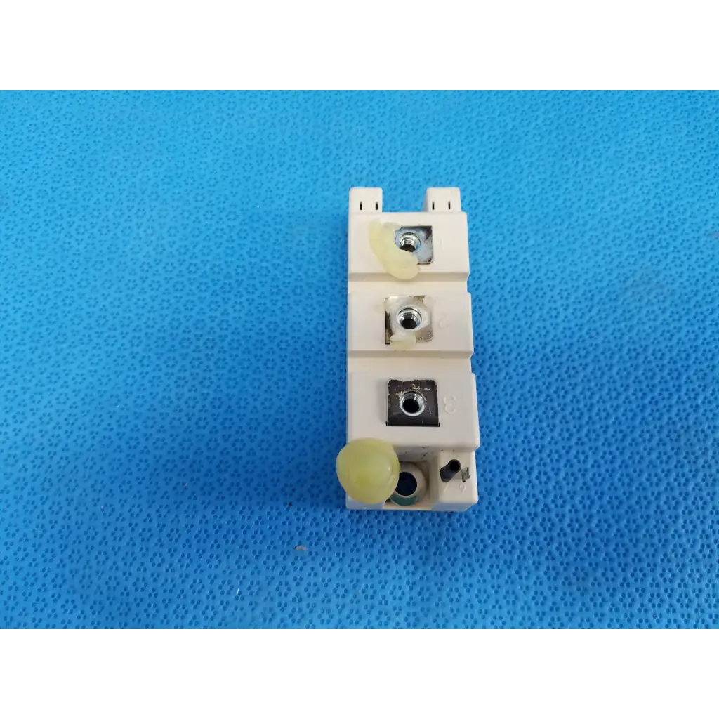 Off-white plastic electrical terminal block with three metal screws and yellow caps on semikron igbt power module