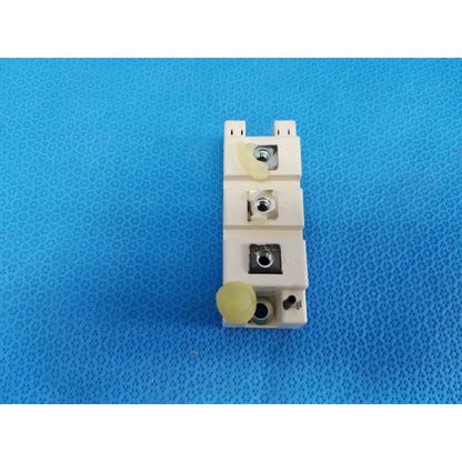 Off-white plastic electrical terminal block with three metal screws and yellow caps on semikron igbt power module
