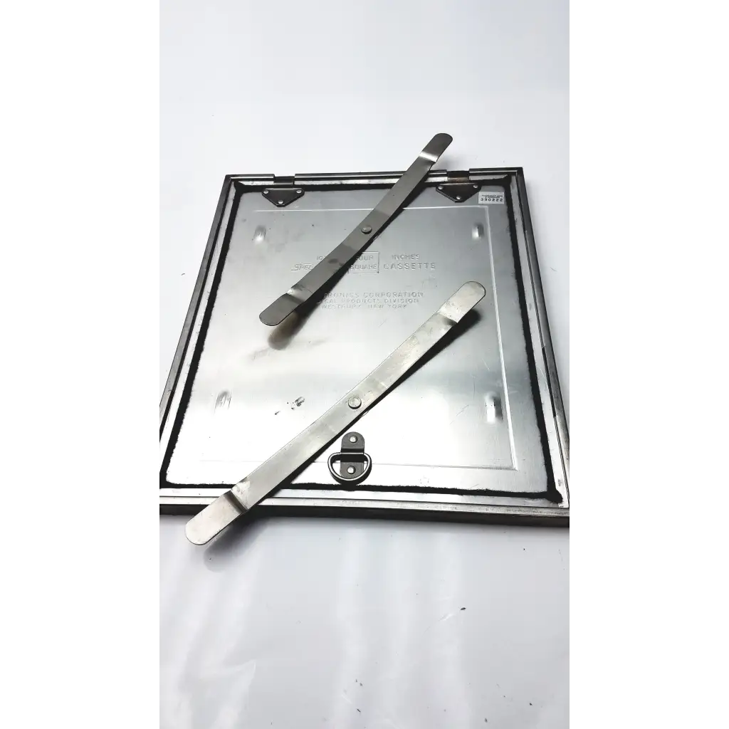 Silver metallic square manhole cover with two lifting bars on top for spectroline 10x12 radiographic cassette use