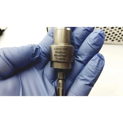 A metallic hudson modified trinkle tool with engraved markings held in a gloved hand for a large bone battery powered drill