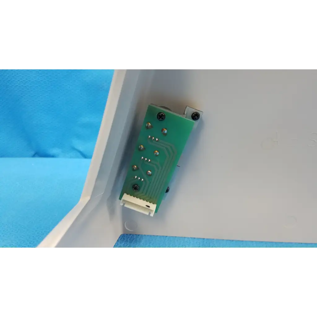Green rectangular circuit board with silver screws and white connector on the back side of trc-nw6s retinal camera housing body shroud