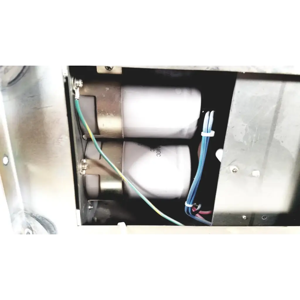 Two white cylindrical capacitors with metallic ends secured by wires inside metal enclosure of toshiba ra power rad92-1008 power supply