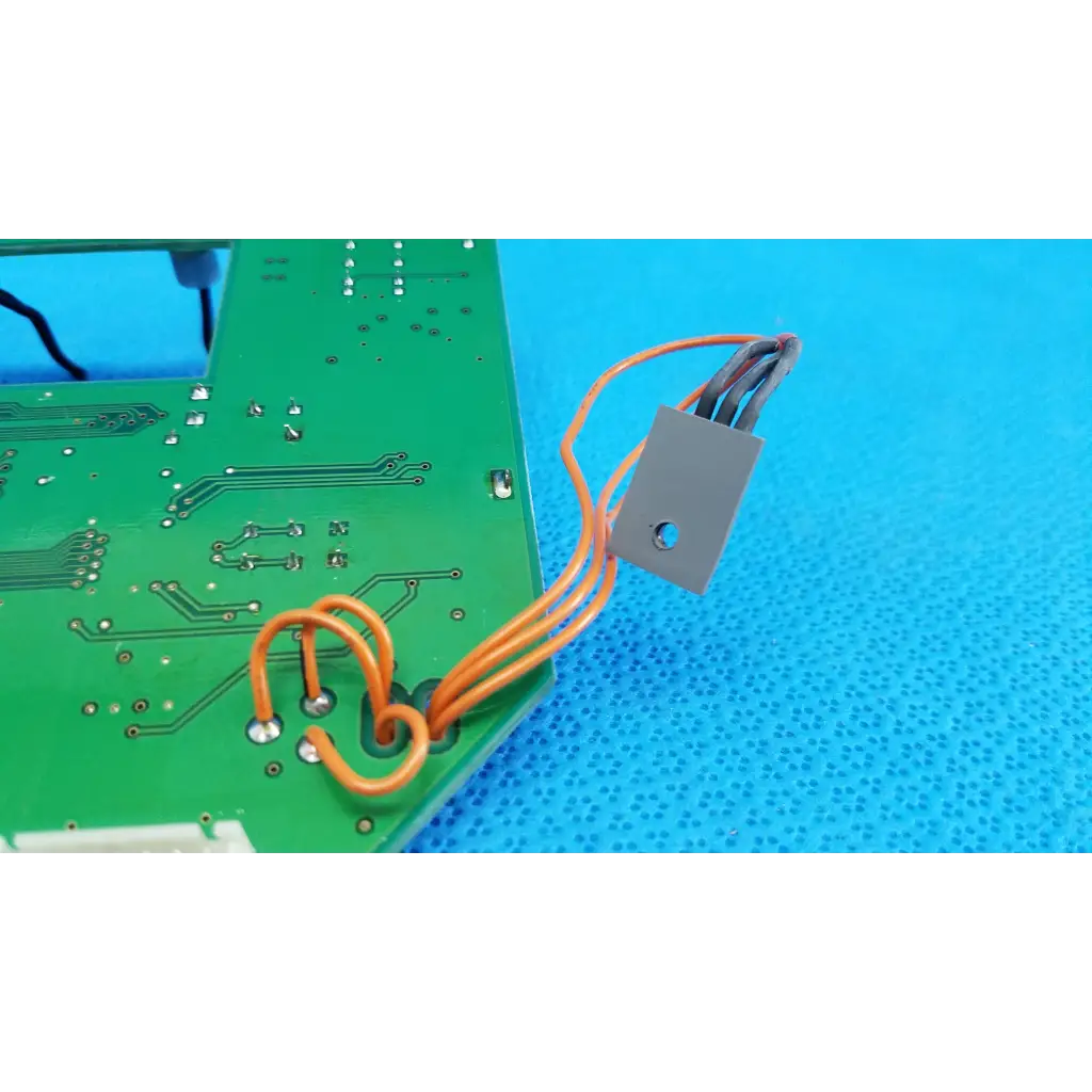 Gray rectangular heat sink with orange insulated wires connected to a green video interface circuit board for topcon retinal camera