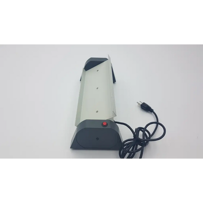 Gray and black unico test tube rocker security camera with red power button and coiled black cable visible from the back side