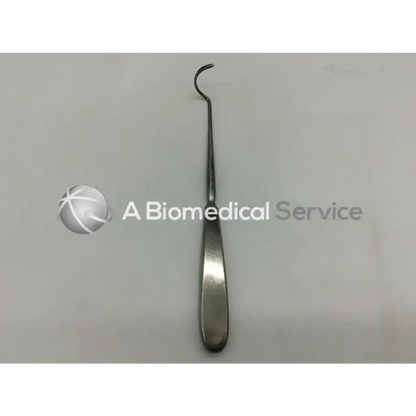 A sleek metallic su3992 deschamps ligature carrier with a curved hook and flat elongated handle for surgical use