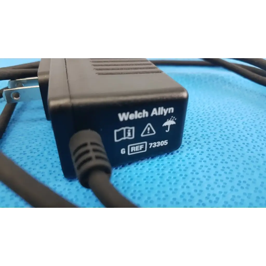 Welch allyn 73305 6v power adapter plug with textured plastic casing and coiled black cord for medical devices