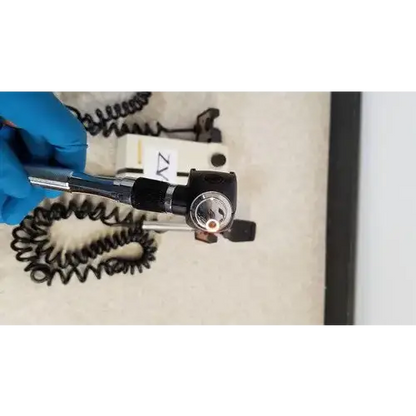 Black Welch Allyn otoscope with circular lens housing and coiled metal cable for wall transformer reuse medical use