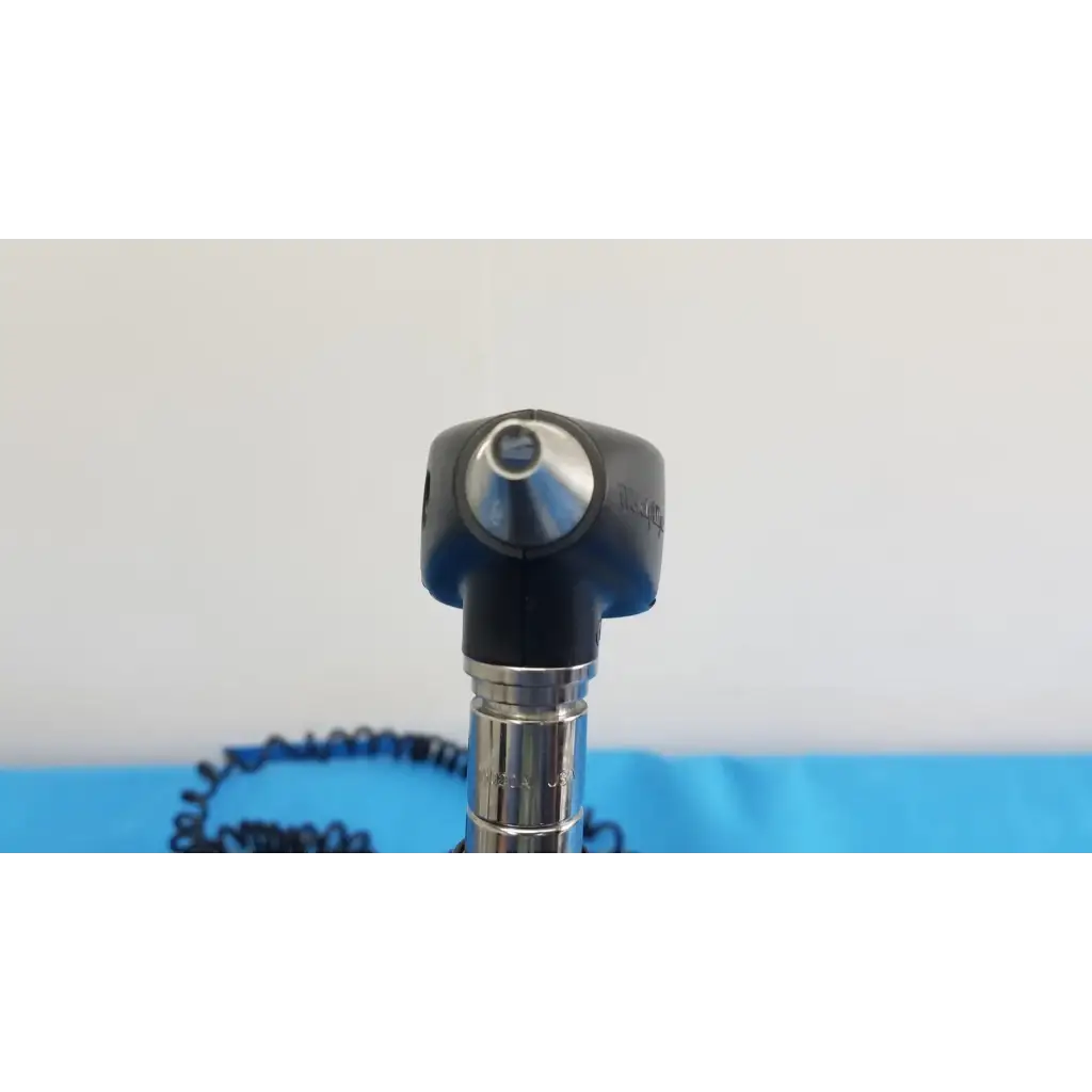 Black and silver otoscope with rounded head metallic shaft and coiled cable from welch allyn 767 series wall transformer