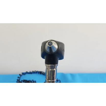 Black and silver otoscope with rounded head metallic shaft and coiled cable from welch allyn 767 series wall transformer