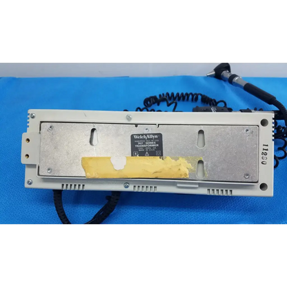 Beige welch allyn 103 series wall transformer with metallic backplate and yellow tape on label for ophthalmoscope use