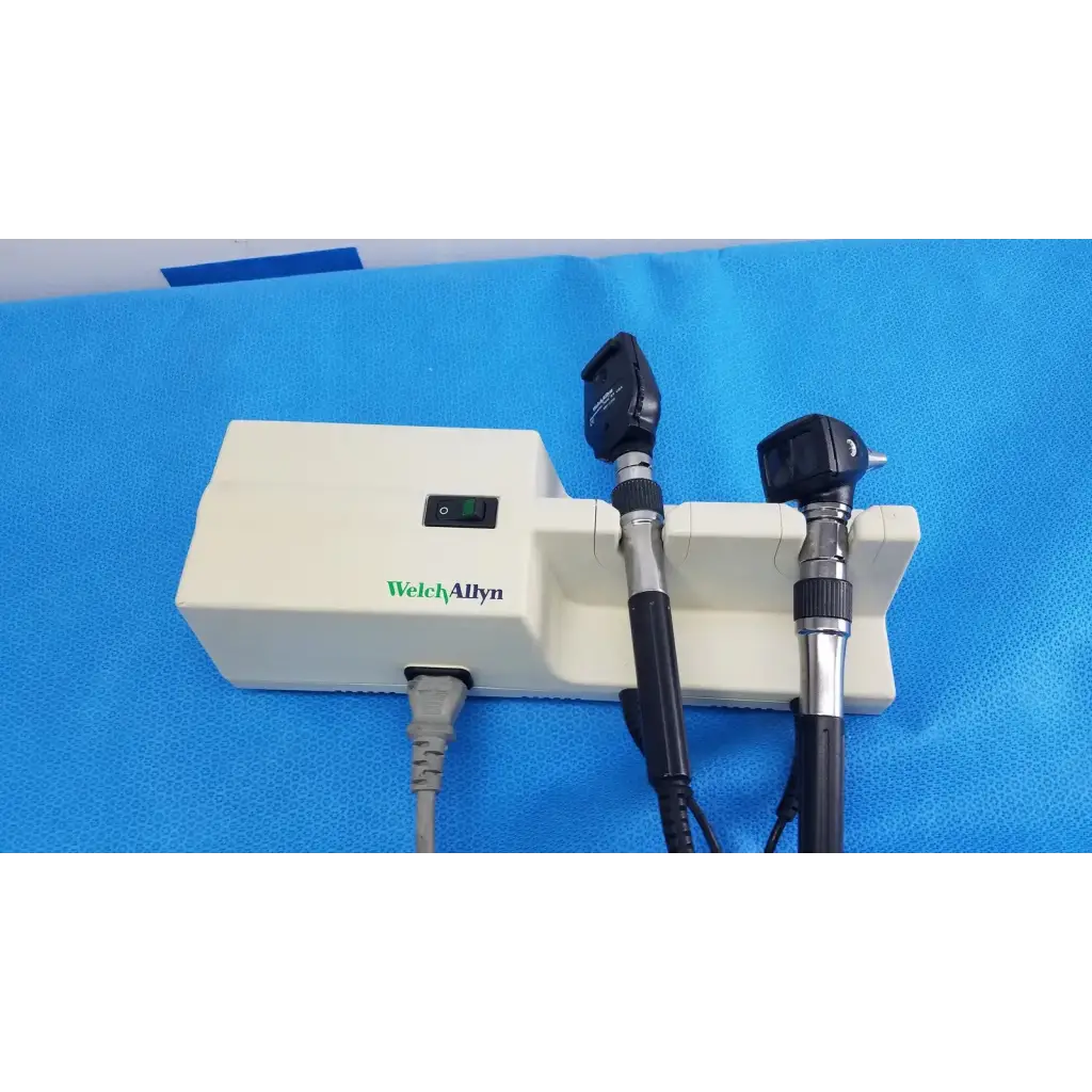 Welch Allyn 767 series wall transformer with black and silver otoscope handles mounted on white base unit