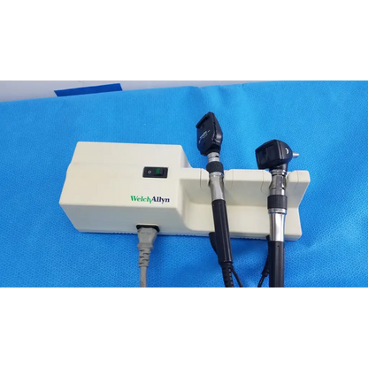 Welch Allyn 767 series wall transformer with black and silver otoscope handles mounted on white base unit