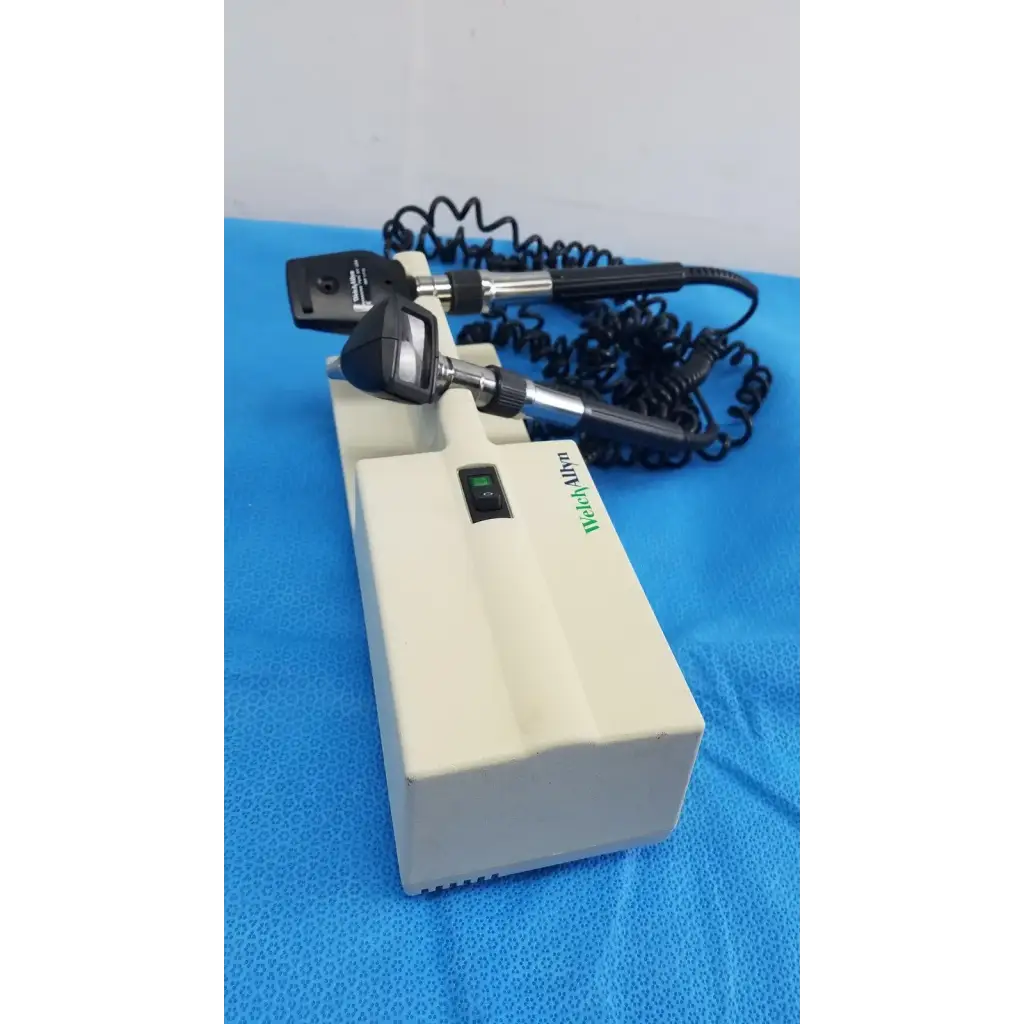 Medical-grade black and silver ophthalmoscope mounted on beige base unit with welch allyn 767 series wall transformer