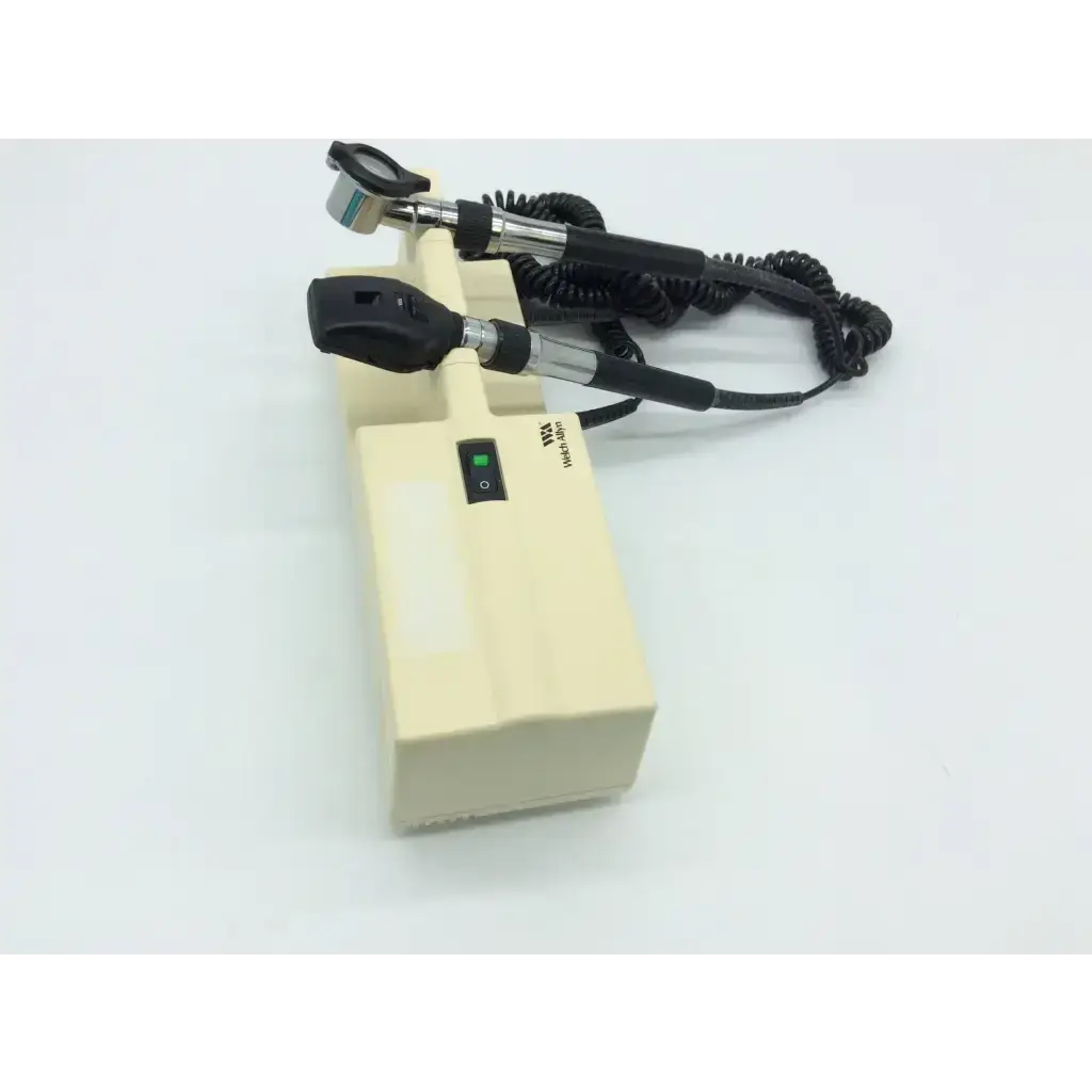 Cream-colored otoscope with black handles and coiled cord attached to welch allyn 767 series wall transformer