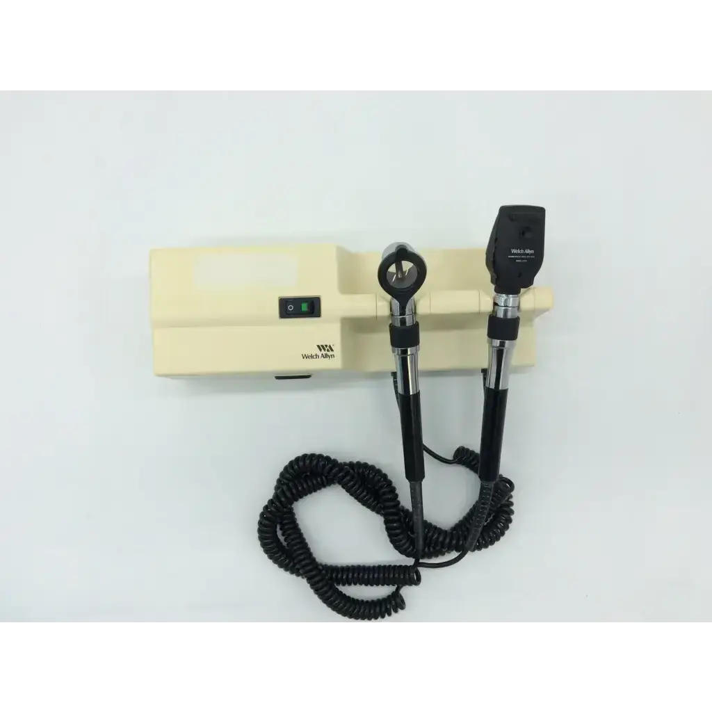Black and silver welch allyn ophthalmoscope with coiled cord on beige beige series wall transformer base