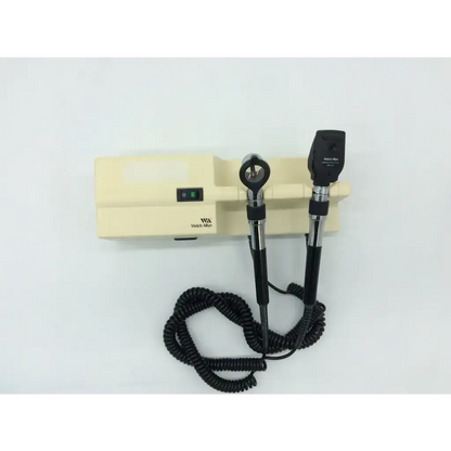 Black and silver welch allyn ophthalmoscope with coiled cord on beige beige series wall transformer base