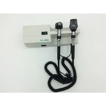 Black and silver welch allyn ophthalmoscope with coiled cord mounted on white welch allyn wall transformer 25020a unit