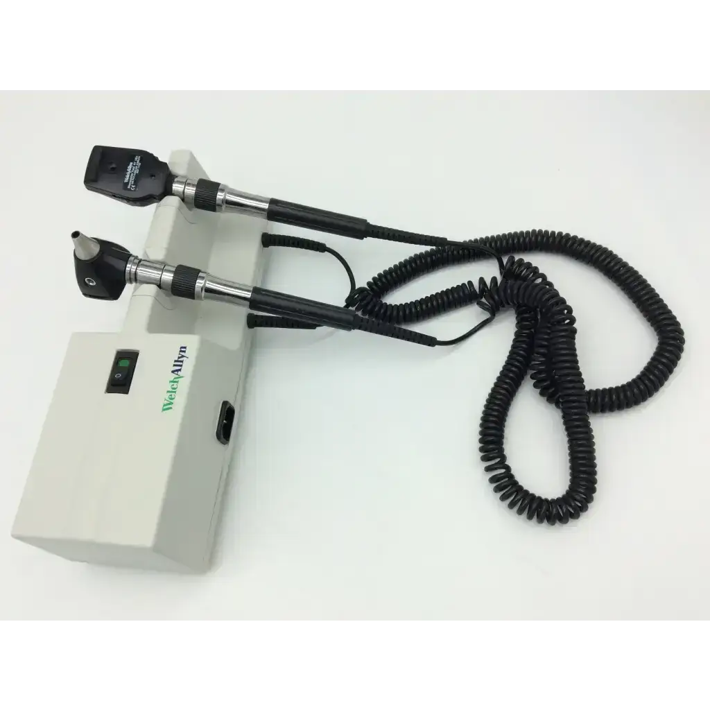 Medical-grade Welch Allyn otoscope with black and silver handles, coiled cable, and beige Welch Allyn 767 Wall Transformer 25020A base unit