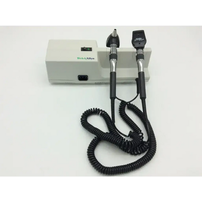 Welch allyn ophthalmoscope with black and silver handles and coiled cable on white base for wall transformer 25020a use