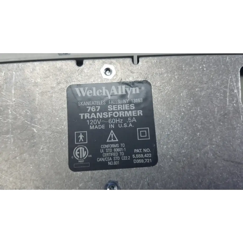 Black rectangular label on metallic surface identifies welch allyn 767 wall transformer for reuse medical devices