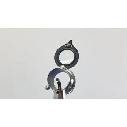 Black-rimmed magnifying glass with metallic reflective base and hinge in welch allyn wall transformer with coaxial ophthalmoscope