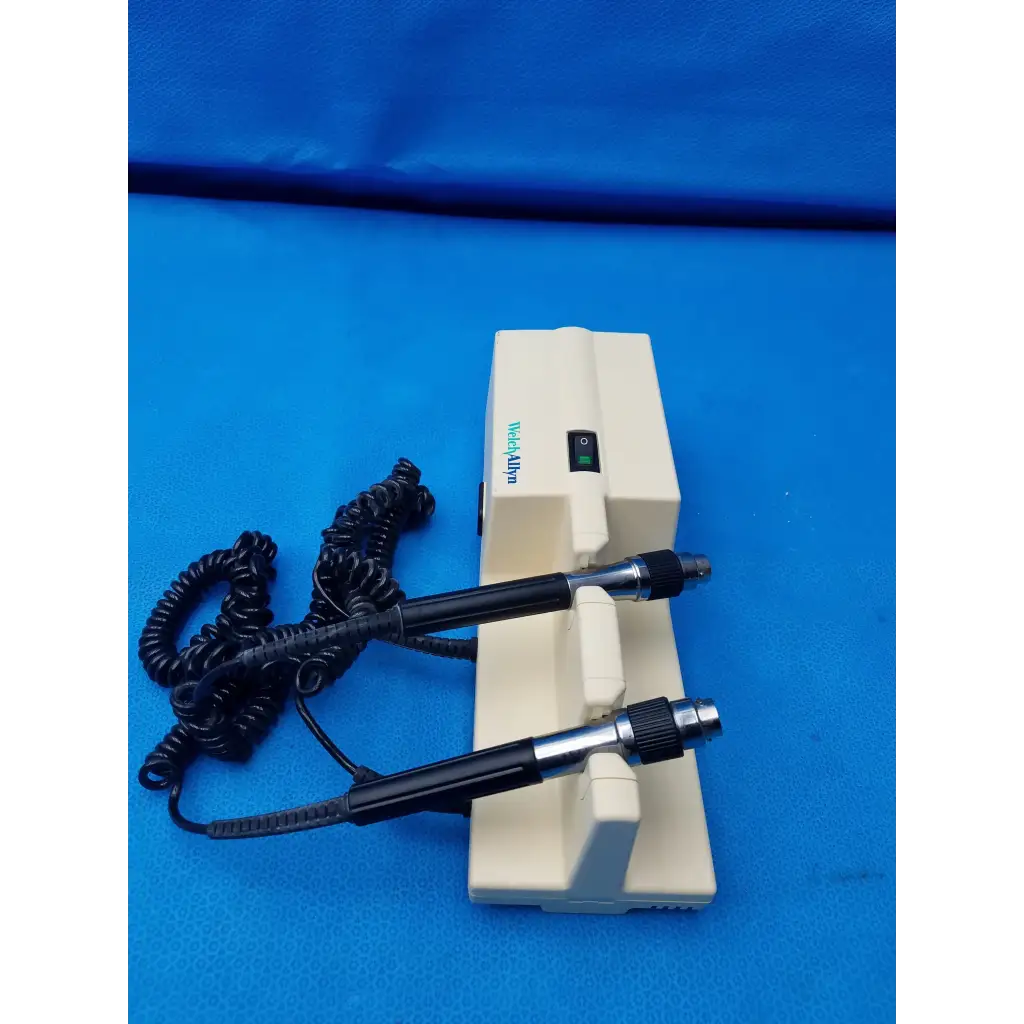 Cream-colored welch allyn diagnostic wall transformer with two black-handled probes and coiled cord no heads visible