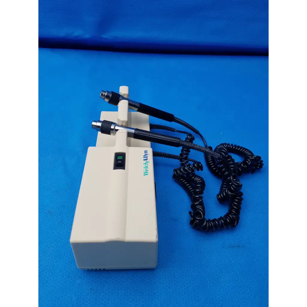 Cream-colored Welch Allyn diagnostic wall transformer with two black-handled probes and coiled black cable no heads