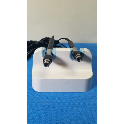 White plastic stand holding two black and silver handheld welch allyn wall transformer medical devices with coiled cords