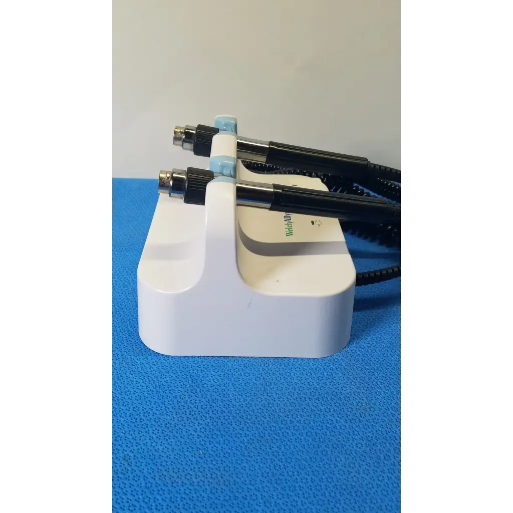 Welch allyn white plastic medical wall transformer stand holding two black and light blue handheld examination tools