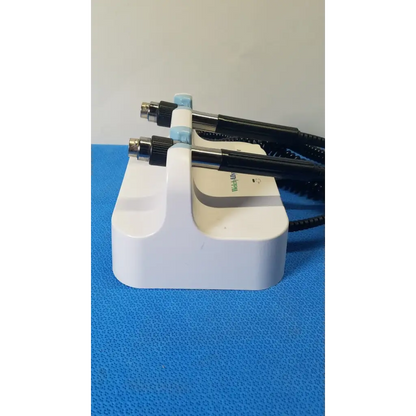 Welch allyn white plastic medical wall transformer stand holding two black and light blue handheld examination tools