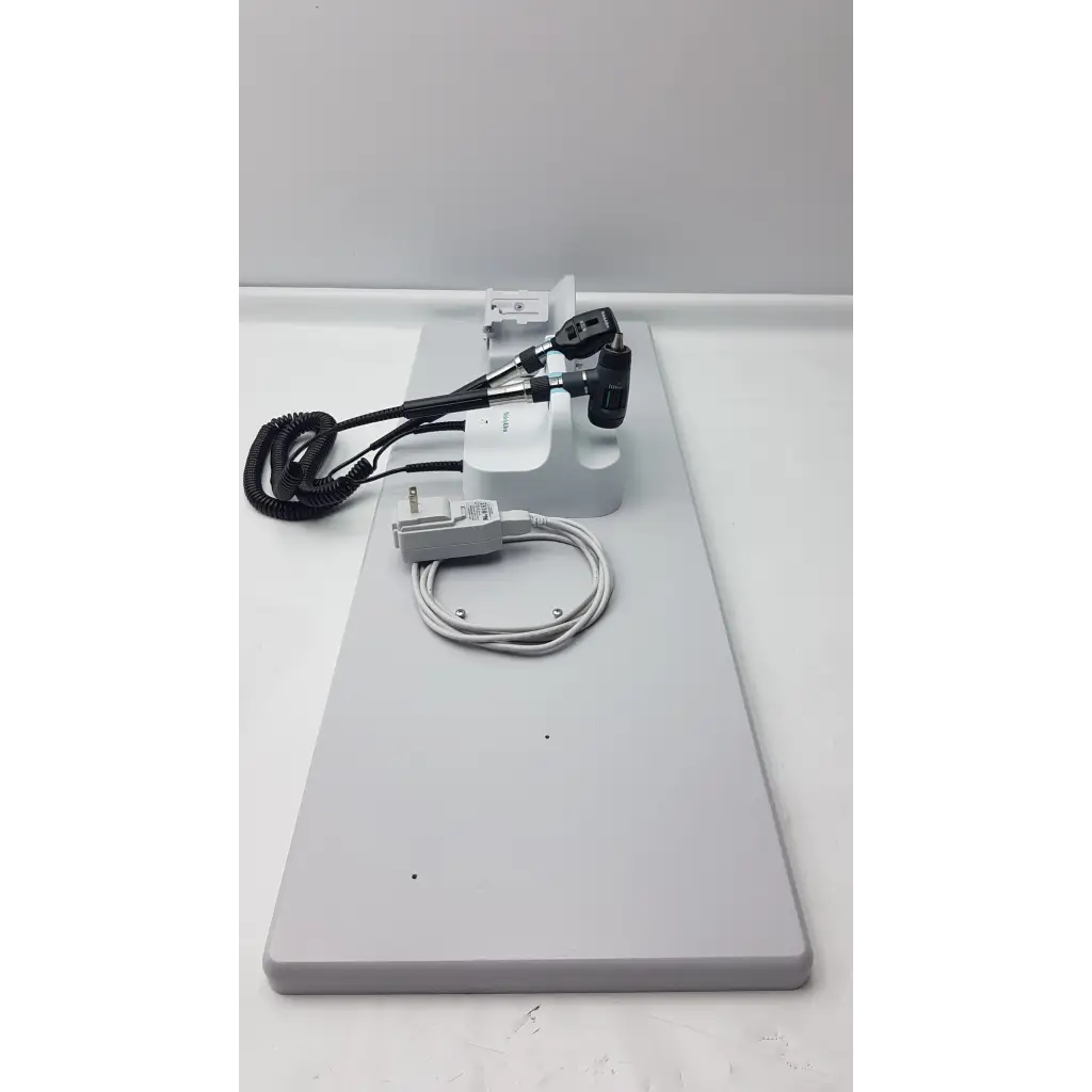 White medical otoscope with black handle and coiled cables on gray stand from welch allyn wall transformer diagnostic set