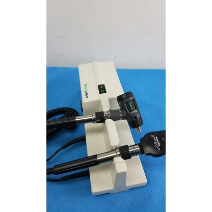 White plastic welch allyn wall transformer stand holding two black and silver otoscope and ophthalmoscope heads