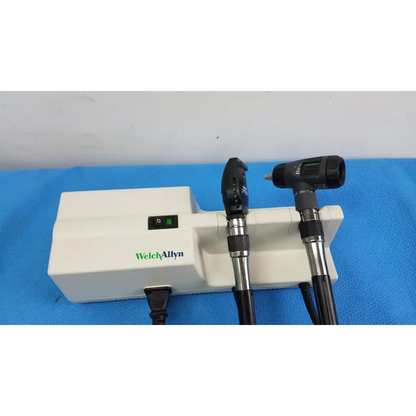 Welch allyn wall transformer with black and silver Welchallyn otoscope handles mounted on a white base unit